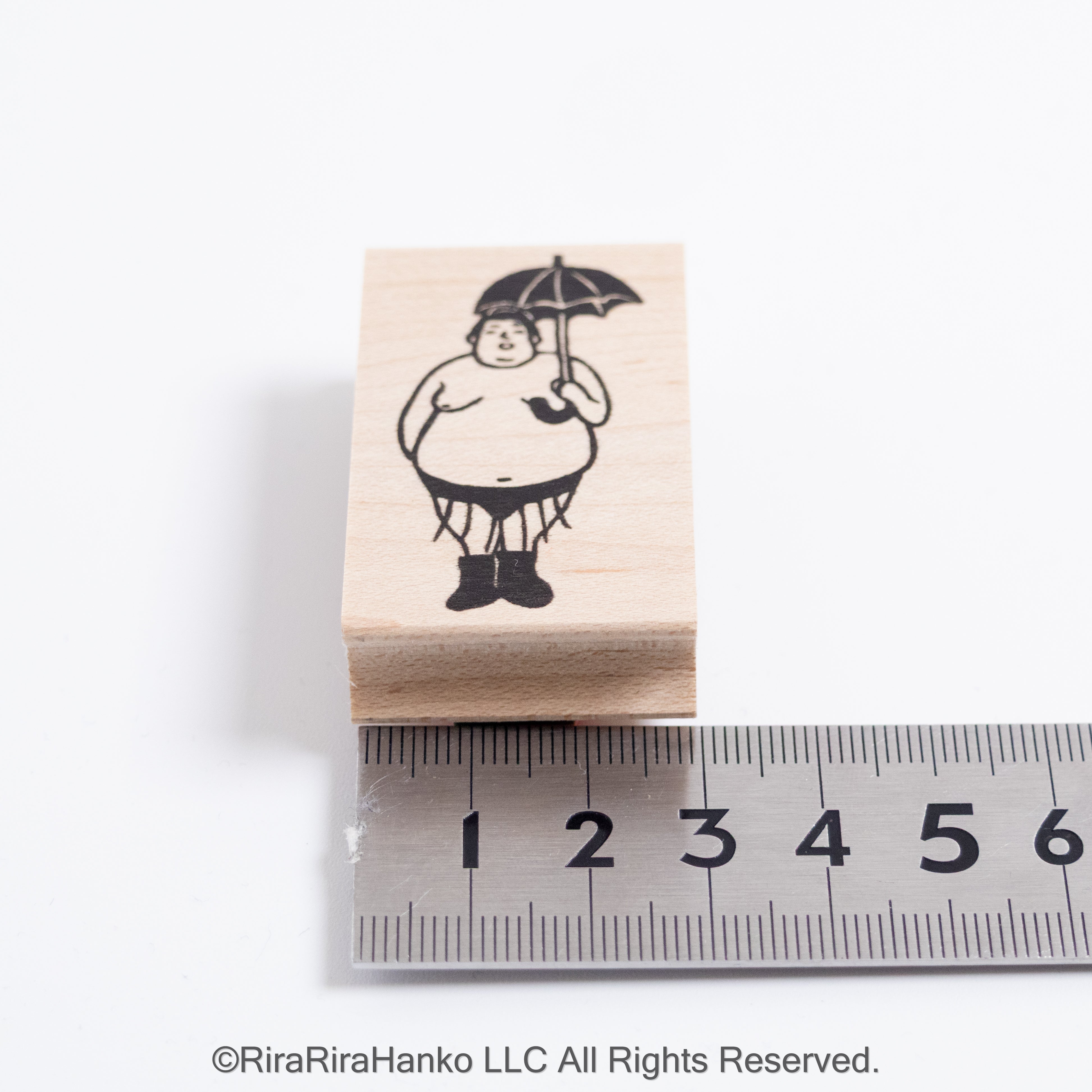 A sumo wrestler holds an umbrella